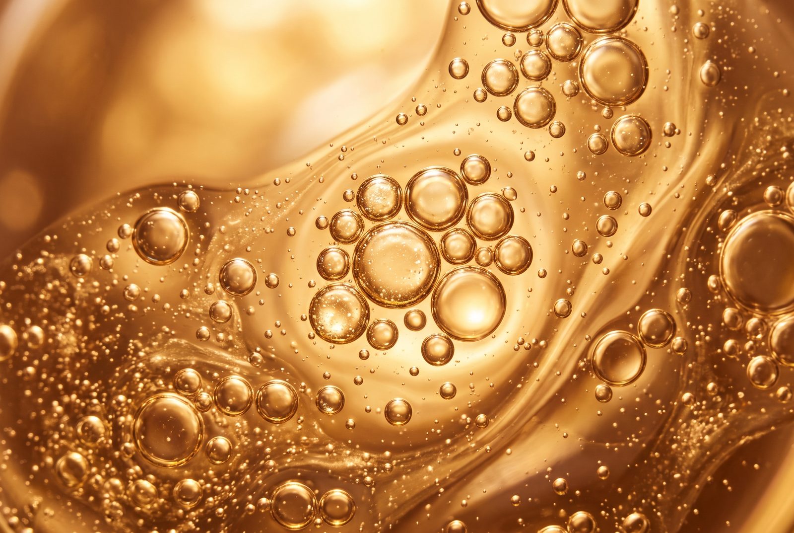 Golden serum macro with droplets of different sizes representing hyaluronic acid molecular weights